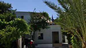A building with a white exterior, a visible garage door, and a small porch area. - "spyros" 1-room Apartment - Simple, Cozy, Close to the Beach (Chania)