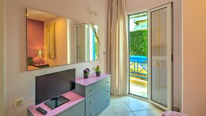 A hotel room with a large mirror, a flat-screen TV, a dresser, and a sliding glass door to a balcony. - Cozy Apartment Amoudara Heraklion Crera-4 (Malevizi)