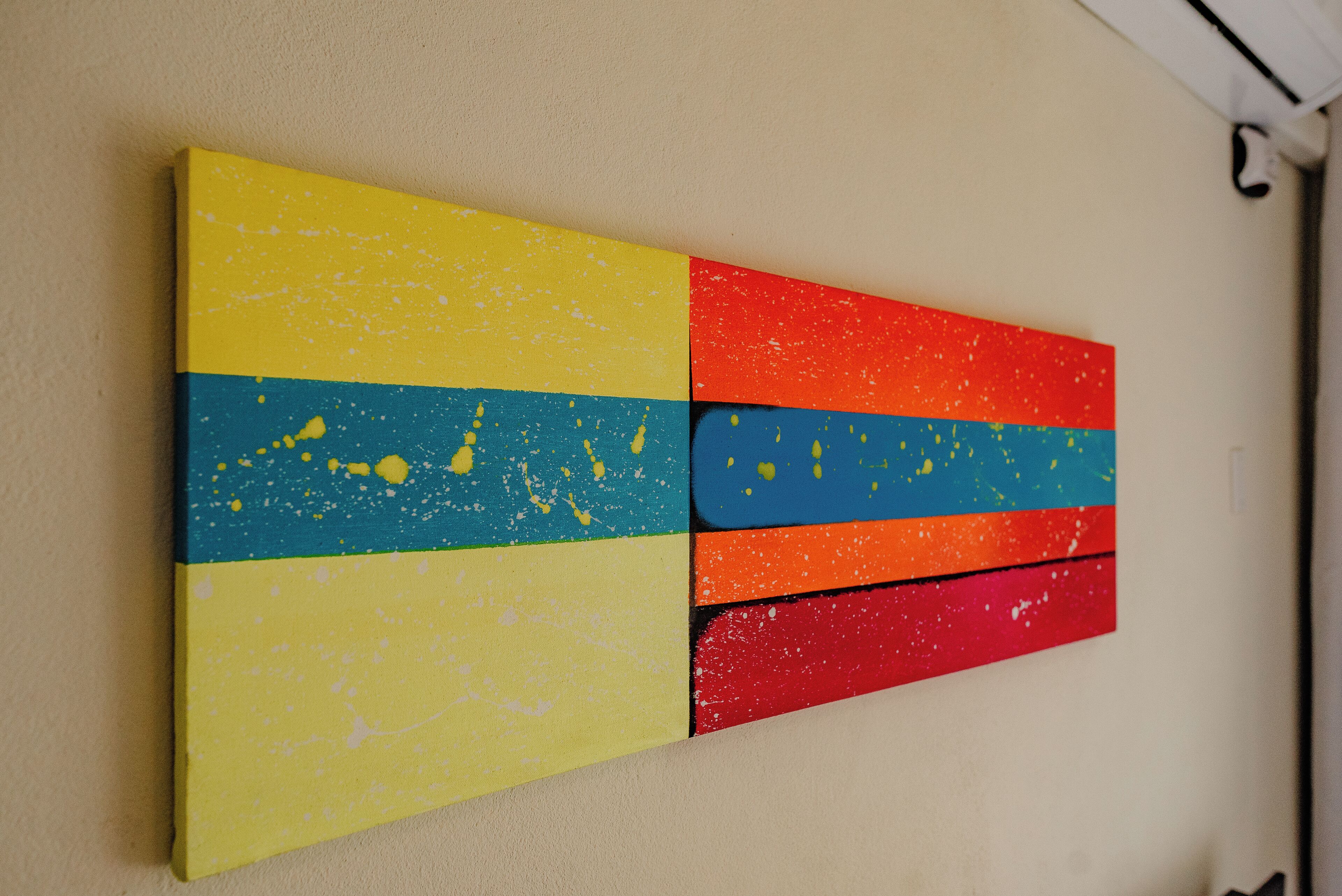 Un mur orné d’un grand tableau abstrait aux couleurs vives.
