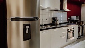 A modern kitchen with stainless steel appliances, white cabinets, and a red accent wall. - Charming 1-bedroom Apartment 2 km From Eagle Beach (Noord)