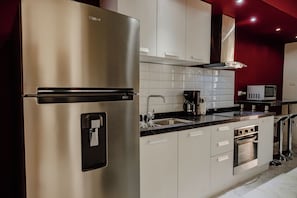A modern kitchen with stainless steel appliances, white cabinets, and a red accent wall.