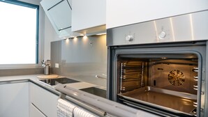 Une cuisine moderne dotée d’appareils électroménagers en acier inoxydable, d’un four encastré et d’une fenêtre laissant entrer la lumière naturelle.