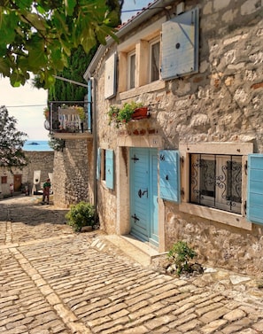 Experience the charm of a traditional building with a balcony, potted plants, and a small garden area.