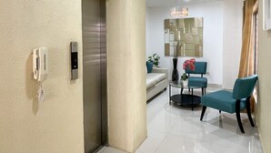 A modern living room with a sofa, chairs, a coffee table, and a decorative vase. - Apto En Zona Privilegiada De Santo Domingo City (Santo Domingo)