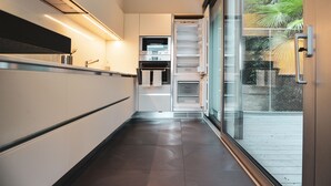Uma cozinha moderna com eletrodomésticos embutidos, uma porta de vidro que dá para uma varanda e um design limpo e minimalista.