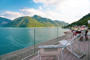 A balcony with chairs overlooking a lake and mountains.