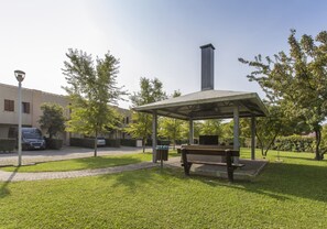 Un espace extérieur abrité avec des sièges, un banc, une poubelle et un lampadaire.