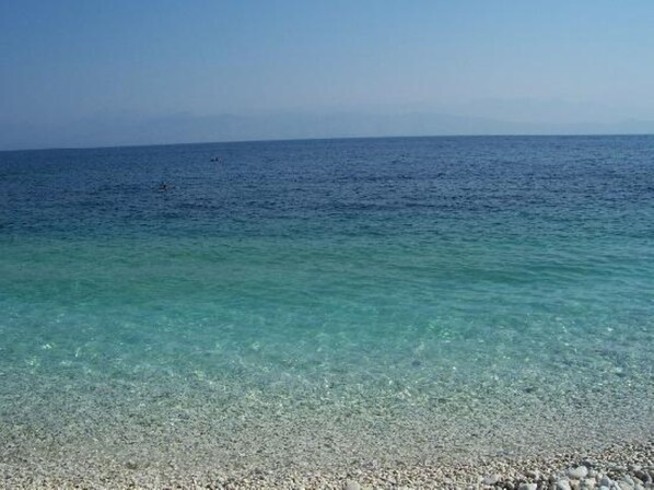 A clear view of a pebble beach leading to calm sea waters. - The Exquisite - Heartbreaking sea and Landscape in Corfu - Greece (Corfu)