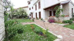 A courtyard with a paved walkway, surrounded by a garden with various plants and flowers. - Liliana One-bedroom Apartment (Rovinj)