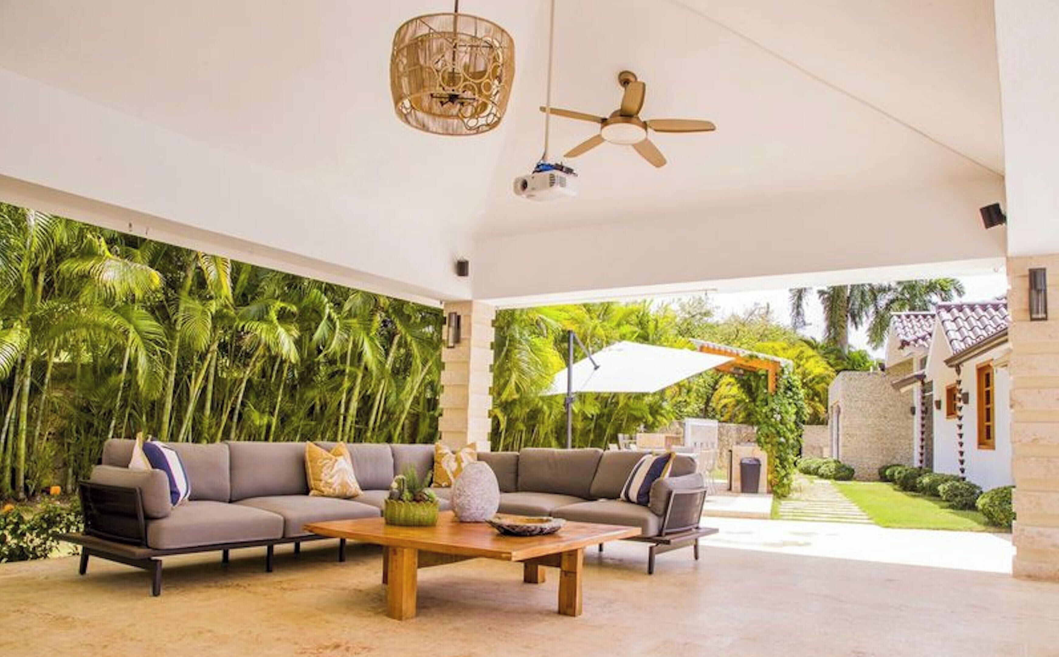A spacious living area with a large sofa set, a wooden coffee table, and a ceiling fan.