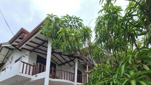 Ein zweistöckiges Haus mit Balkon, einer gefliesten Terrasse und Kübelpflanzen.