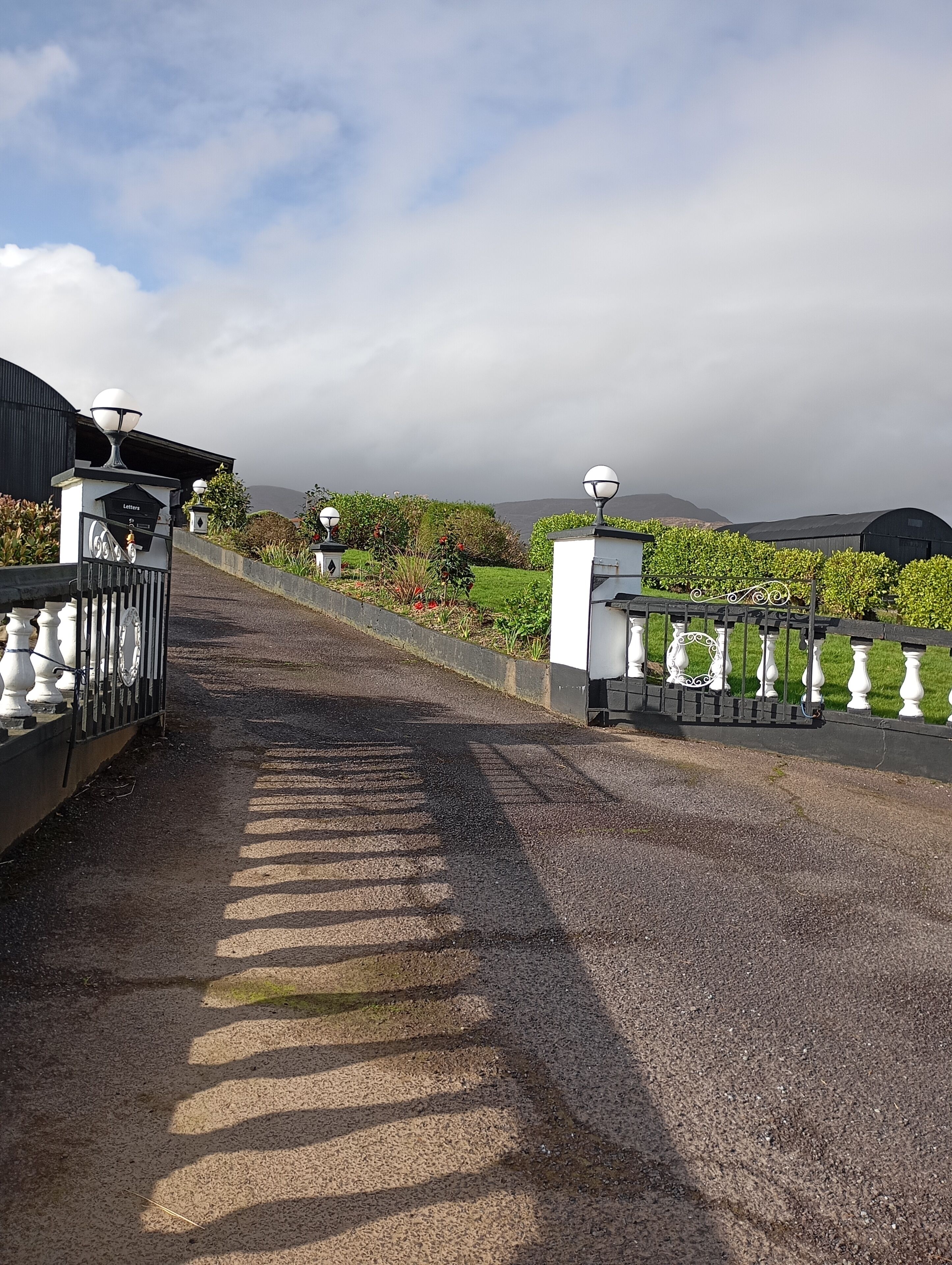 A gravel pathway leading to a gated entrance with a sign reading "Letters."