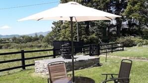 An outdoor patio with a round table and four chairs, an umbrella, and a stone wall in the background. - Room in Apartment - 1 Bedroom In A Homely Home With A Lovely Farm (Sneem)