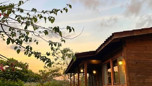 Una baita di legno con un portico, una scala e vista sul verde circostante.
