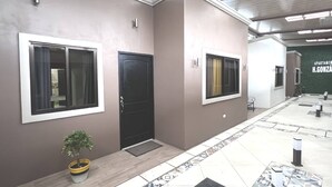 A hallway with a black door, a potted plant, and a tiled floor with a geometric pattern. - Tuareg Place Aeropuerto A,C (Alajuela)
