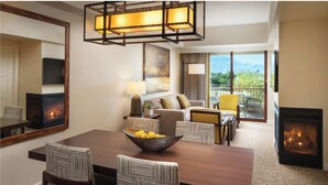 A modern living room with a fireplace, a dining area with a wooden table and striped chairs, and a balcony with a view of mountains. - Westin Desert Willow Villas, Palm Desert (Palm Desert)