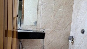 Uma casa de banho com sanita, lavatório e chuveiro.