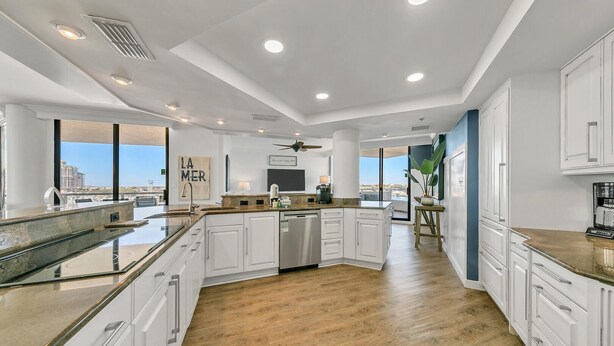 Una cocina moderna con armarios blancos, una isla central y vistas de la ciudad.