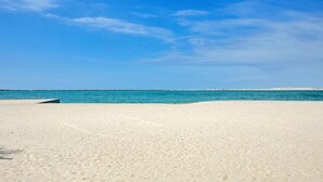 Una playa extensa y arenosa, con un mar tranquilo y cielo despejado.