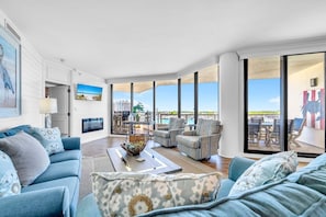 A spacious living room with a large window, a sofa, a coffee table, and a dining area with chairs.