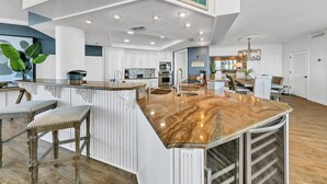 Una cocina amplia con una isla grande, armarios blancos y un letrero decorativo sobre la isla.
