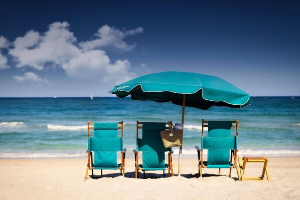 Three beach chairs with canopies line the shoreline.