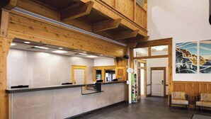 A reception area with a wooden reception desk, a balcony, and a wall with a mountain painting. - Marriott Summit Watch - Ski-In & Ski-Out - Great Location - Sleeps 4 (Park City)