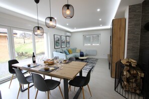 A modern dining area with a wooden table, black chairs, and hanging pendant lights.