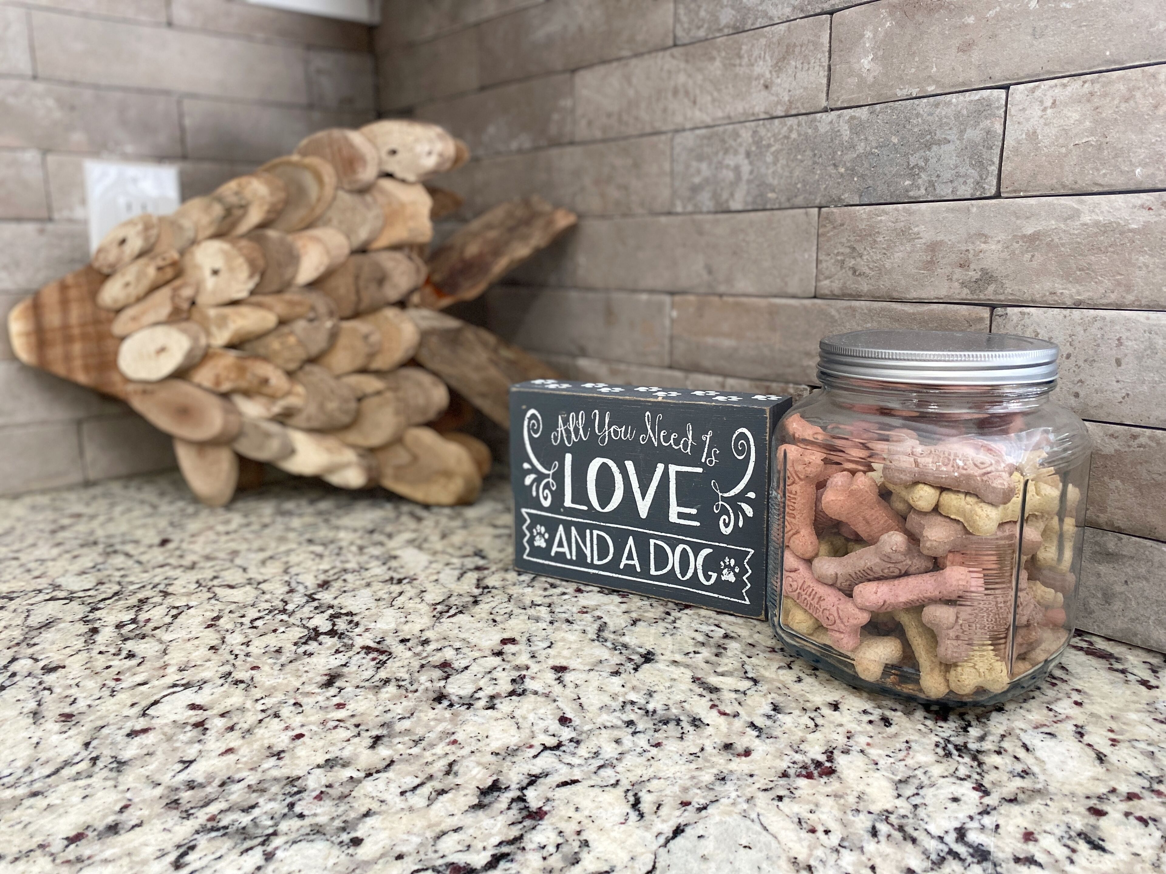 Een keukentafel met een pot hondensnoepjes en een bord waarop staat: "All You Need Is LOVE AND A DOG".