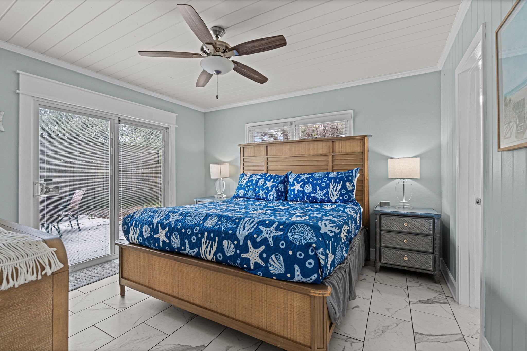 A bedroom with a bed, a ceiling fan, a nightstand, and a window with blinds.
