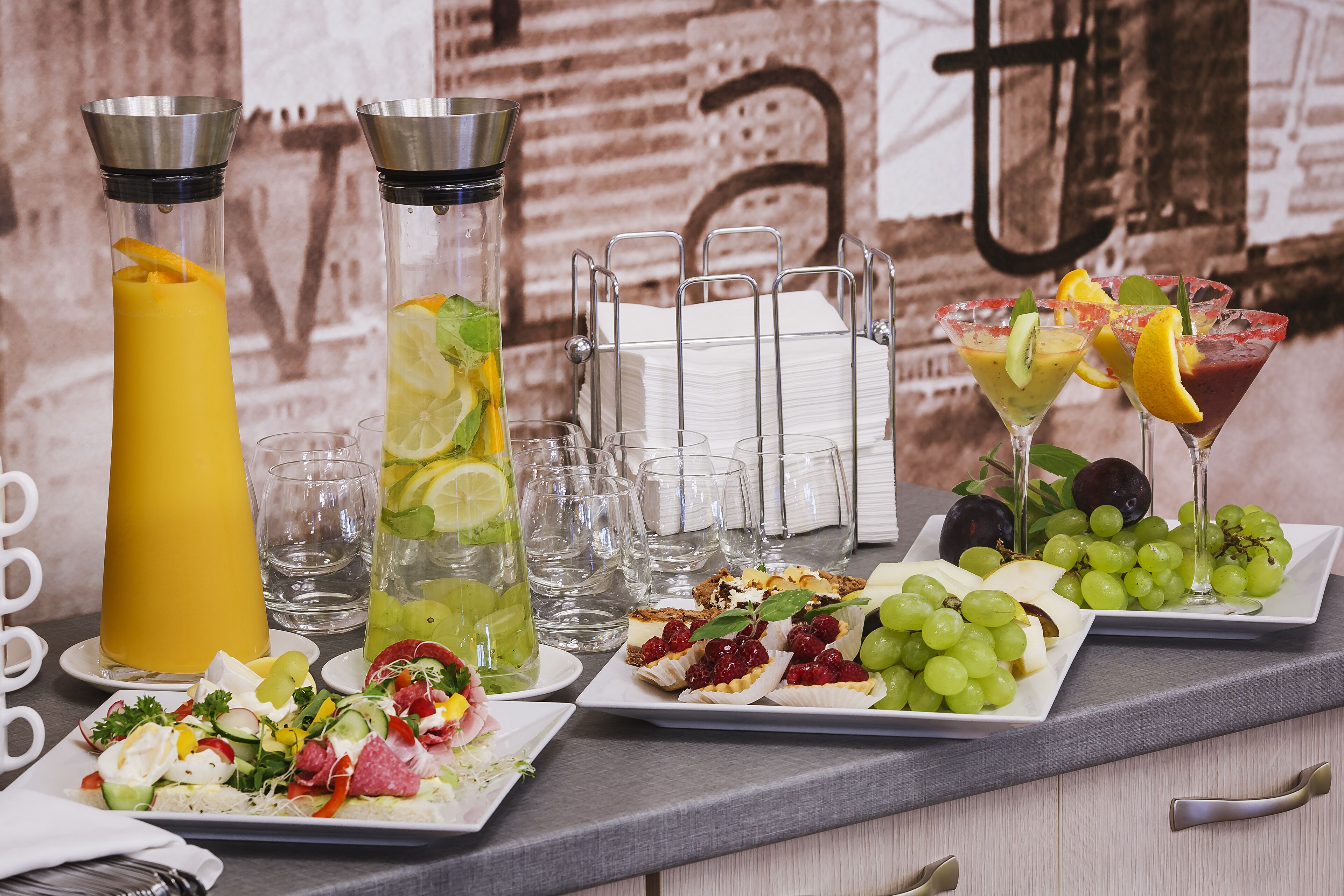 Un bufé de desayuno con diversas opciones de comida, bebidas y una pared decorativa.