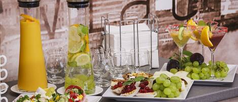 Un bufé de desayuno con diversas opciones de comida, bebidas y una pared decorativa.