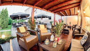 An outdoor patio area with wicker furniture, umbrellas, and potted plants. - Citi Hotel's Warszawa-Falenty (Raszyn)
