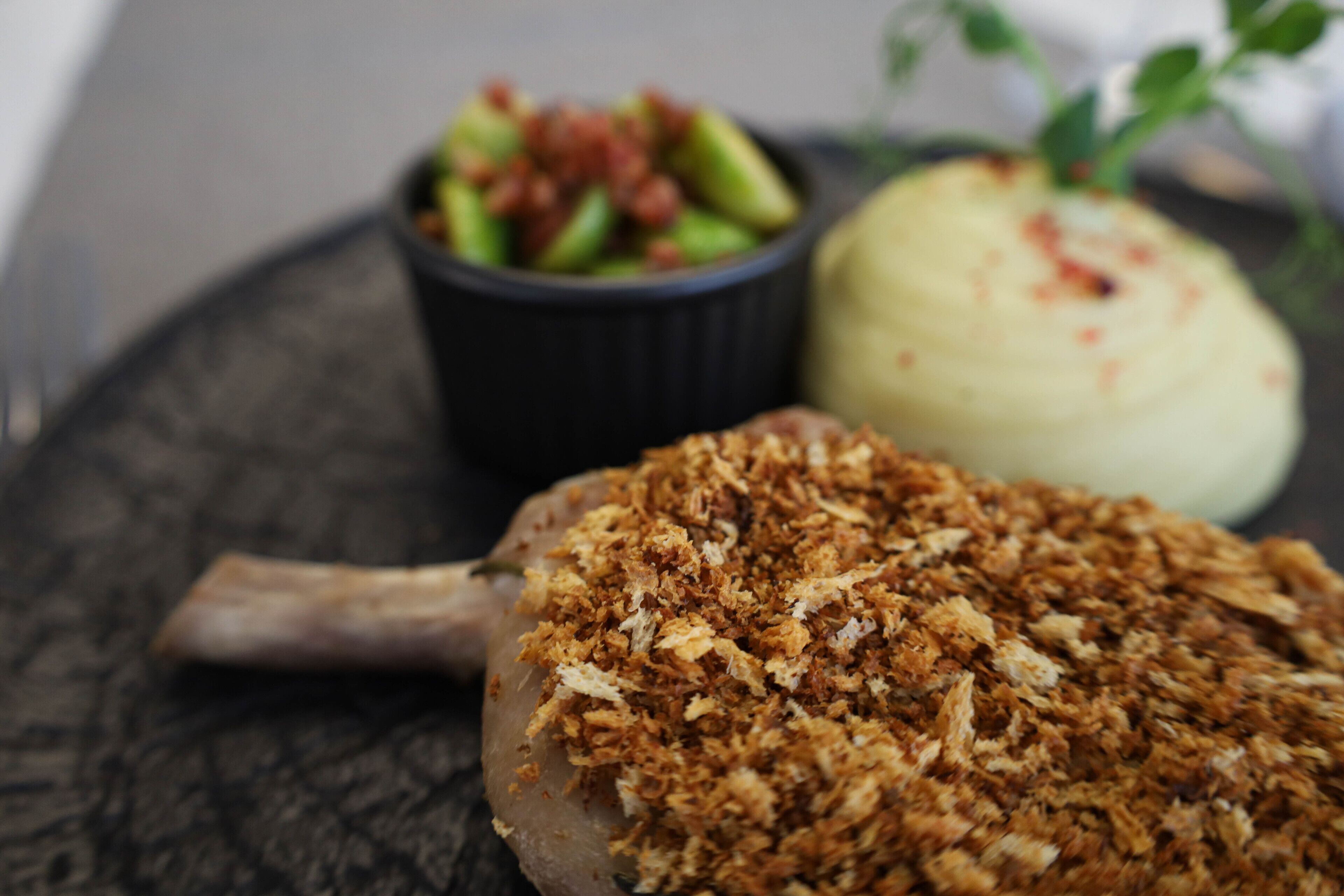 A plate with a meat dish, a bowl of salad, and a mound of mashed potatoes.