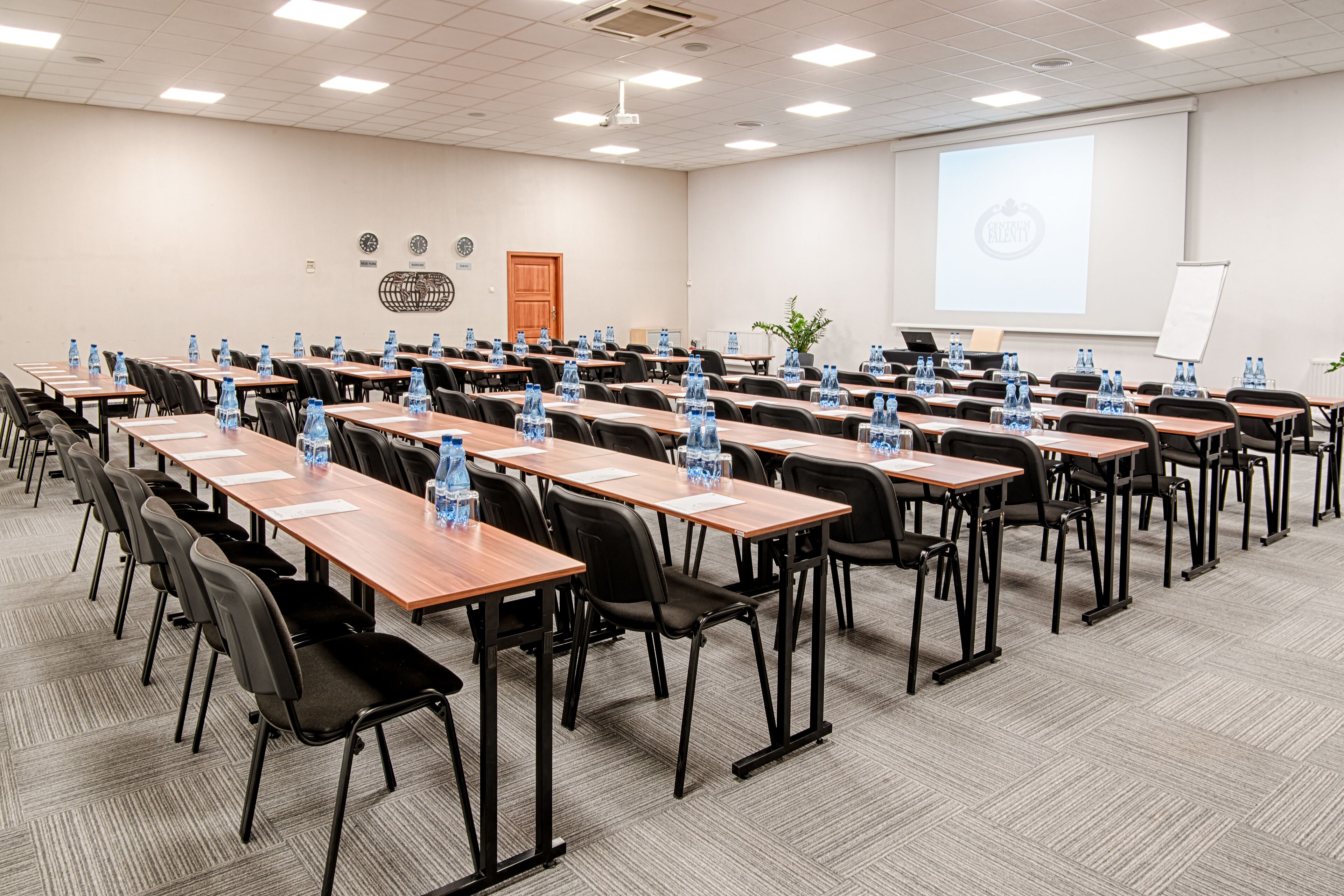 A conference room with rows of tables, chairs, and water bottles.