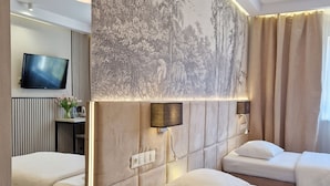 A modern hotel room with a large bed, a smaller bed, a desk, a TV, and a wall with a nature-themed mural. - Citi Hotel's Warszawa-Falenty (Raszyn)