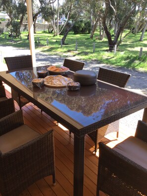 Un tavolo da pranzo con piano in vetro e sedie in vimini, circondato da un pontile in legno.