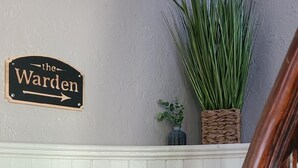 Eine Treppe mit einem Holzgeländer und einem an der Wand befestigten Schild mit der Aufschrift "the Warden".