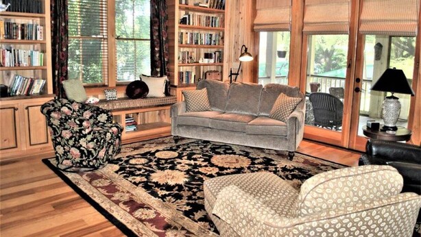 A cozy living room with a fireplace, a sofa, a patterned armchair, and a bookshelf filled with books. - 3 Bdrm in Georgetown's Historic District (Georgetown)