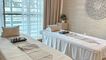 Relax in a serene space with two massage tables, a large window, and a decorative wall art piece.
