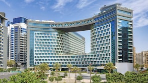 A modern hotel with a curved facade, multiple floors, and a prominent overhang. - NH Collection Dubai The Palm (Dubai)
