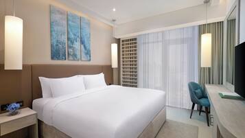 Ein modernes Hotelzimmer mit einem großen Bett, einem Schreibtisch mit Stuhl und Bildern an der Wand.