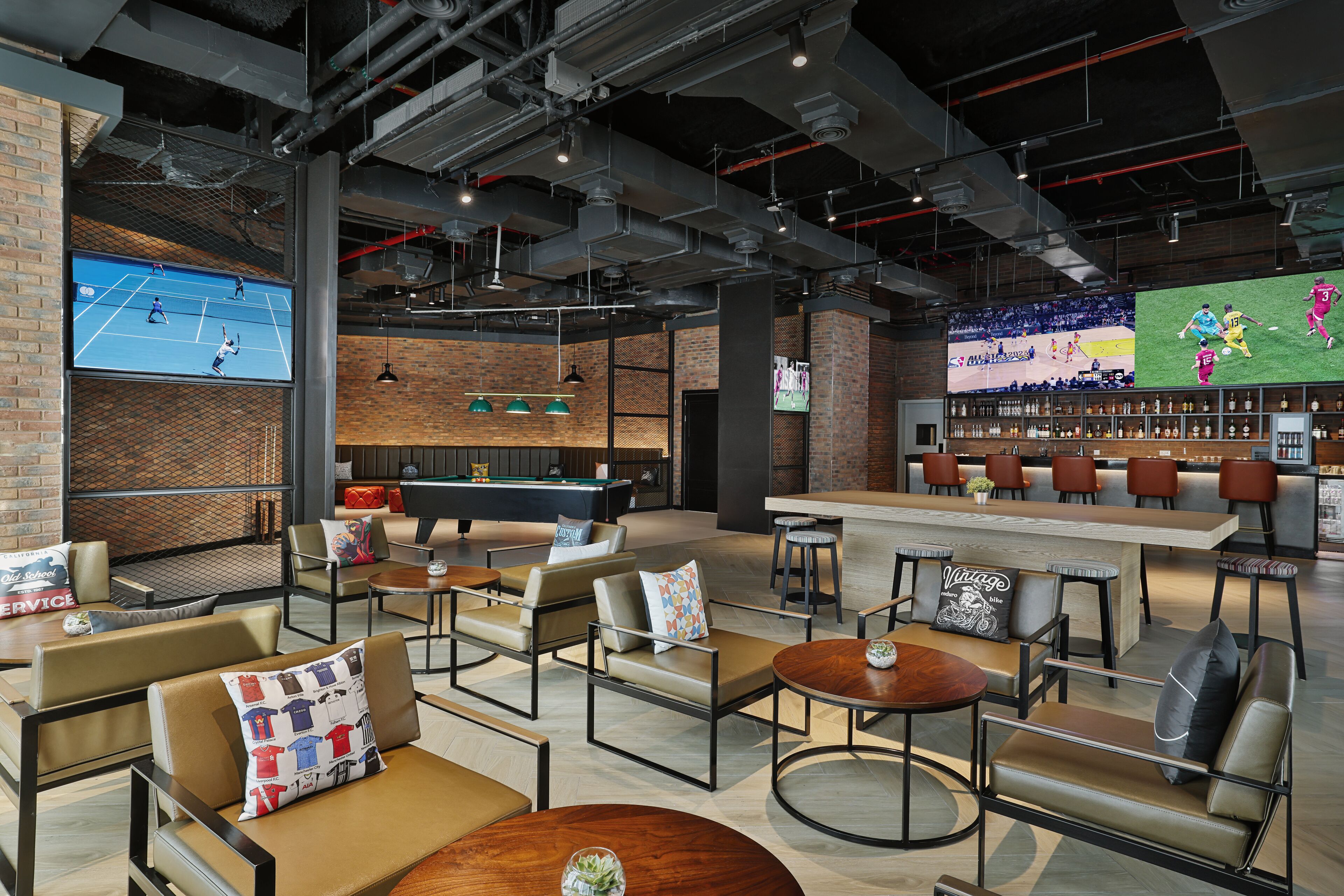 A modern lounge area with leather sofas, a pool table, and a bar with stools.