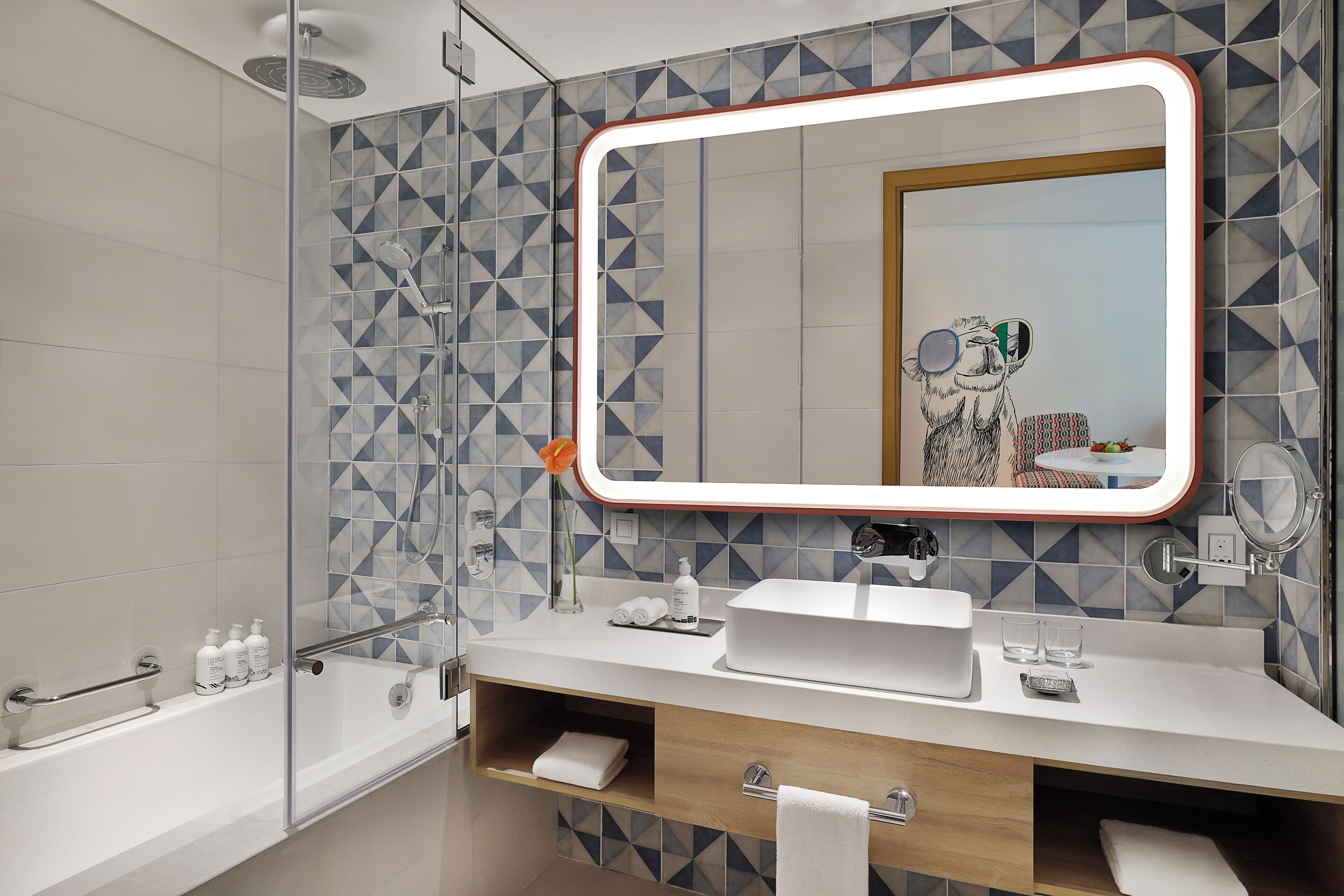 A modern bathroom with a large mirror, a bathtub, a vanity with a sink, and a shower area.
