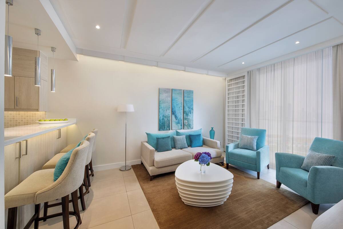 A modern living room with a sofa set, a coffee table, and a kitchen area with bar stools.