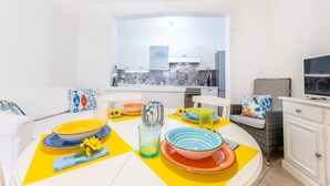 Valoisa, moderni keittiö, jossa on valkoiset kaapit ja laatoitettu välitila.