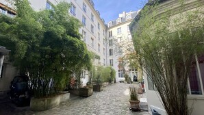 A cobblestone courtyard with potted bamboo plants and a blue pot on the right. - Duplex With Terrasse and vue on the Eiffel Tower (Paris)