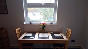 Ein Esstisch mit vier Platzsets, einer Blumenvase und zwei Stühlen.