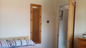 Ein Schlafzimmer mit einem Bett, einer Holztür und einem Schminktisch.