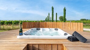 Un jacuzzi en una terraza de madera, con una botella de champán y una toalla.